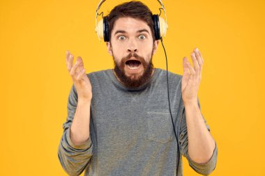 Sakallı adam kulaklığı teknolojisi müzik dinliyor sarı arka plan