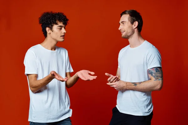 Due uomini allegri su t-shirt comunicazione amicizia rosso sfondo — Foto Stock