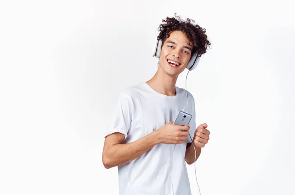 Divertido chico con el pelo rizado en una camiseta blanca escucha música tecnología entretenimiento — Foto de Stock