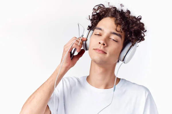 Emotionaler Mann mit lockigem Haar und Kopfhörer hört Musik im Hintergrund — Stockfoto