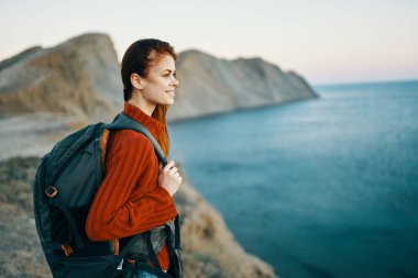 Sırt çantalı kadınlar sırt çantasıyla okyanus manzarasında seyahat ediyorlar.