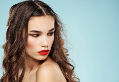 Kadın model esmer, kırmızı dudaklı, göz kapaklarında far var.