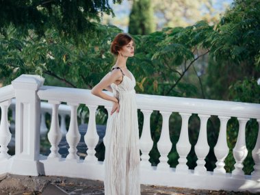 Beyaz elbiseli güzel bir kadın geleneksel Yunan kıyafetleri yeşil yapraklar