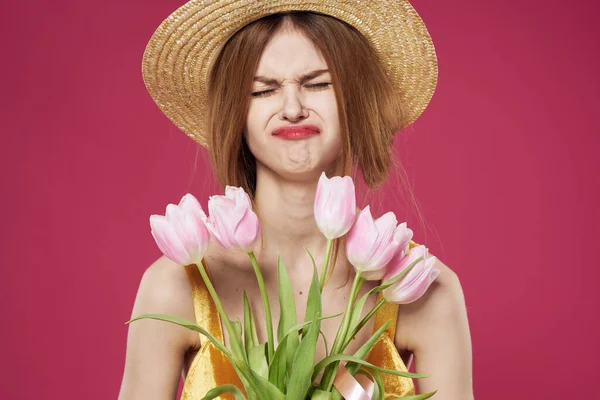 Glada kvinna i en hatt klänning och en bukett blommor rosa bakgrund närbild — Stockfoto