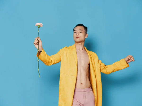 Homem com flor no fundo azul e casaco amarelo nu torso corte vista — Fotografia de Stock