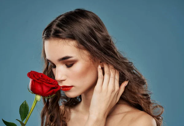 Portrait d'une belle femme avec une fleur rouge sur fond bleu et modèle de maquillage du soir — Photo