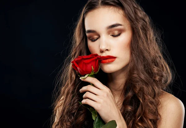 Romantische vrouw op zwarte achtergrond met rode bloem in haar handen — Stockfoto