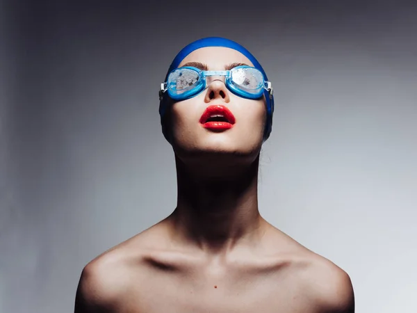 Kırmızı dudaklı, mavi yüzme şapkalı ve gözlüklü sporcu kadın kırpık manzaraya bakıyor. — Stok fotoğraf