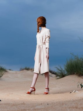 Uzun boylu, kızıl saçlı, yüzünde atkuyruğu olan, kırmızı ayakkabılı bir kadın.