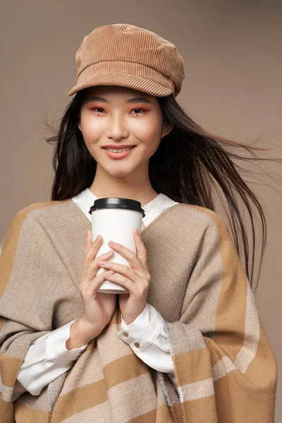 Nő ing és bézs kabát kalap csésze forró ital stílusos ruhák — Stock Fotó