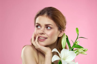 Pembe arka planda çiçekli güzel bir kadın makyaj modeli.