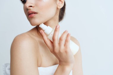 Beyaz havluyla güzel bir kadın çıplak omuzlar losyon temiz cilt hijyeni