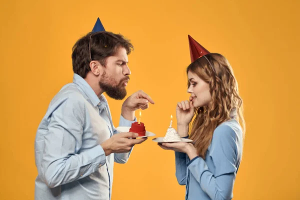 Feliz homem e mulher com bolo de aniversário no fundo amarelo — Fotografia de Stock