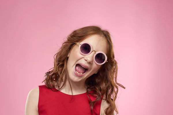 Joyeux petite fille enfance lunettes sombres robe rouge style de vie fond rose — Photo