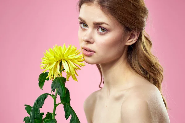 Retrato de una mujer con flores amarillas sobre un fondo rosa Maquillaje en la cara —  Fotos de Stock