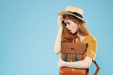 Sırt çantalı güzel bir kadın. Moda kıyafetleri mavi arka planda.