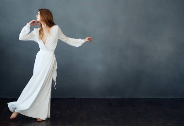 Gri arkaplan üzerinde beyaz elbiseli romantik kızıl saçlı kadın.