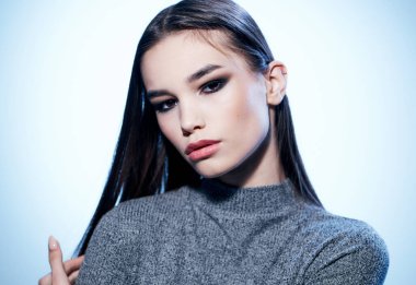 Açık arkaplanda esmer bir kadının portresi yakın plan çekilmiş.