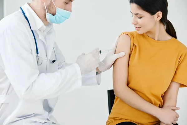 Un médico con guantes protectores para pegar un yeso inyectable en una mujer vacunación covid —  Fotos de Stock