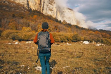 Kadın sonbaharda doğada dinleniyor dağlarda mavi gökyüzü manzarası sırt çantası