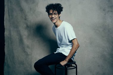 Sandalyede oturan sevimli adam kıvırcık saçlı, gülümseyen yaşam tarzı.