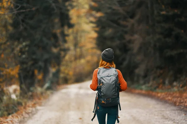 Viajante com uma mochila na floresta na estrada em árvores de outono modelo — Fotografia de Stock