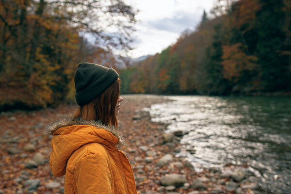 woman hiker admires nature in the mountains autumn river
