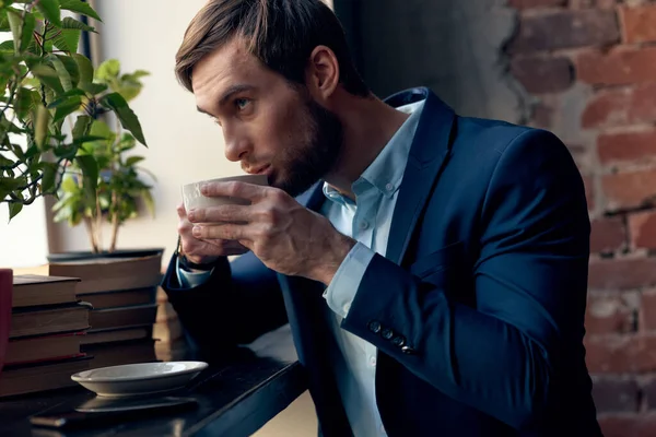 Un homme en costume boit du café près de la fenêtre d'un café. — Photo