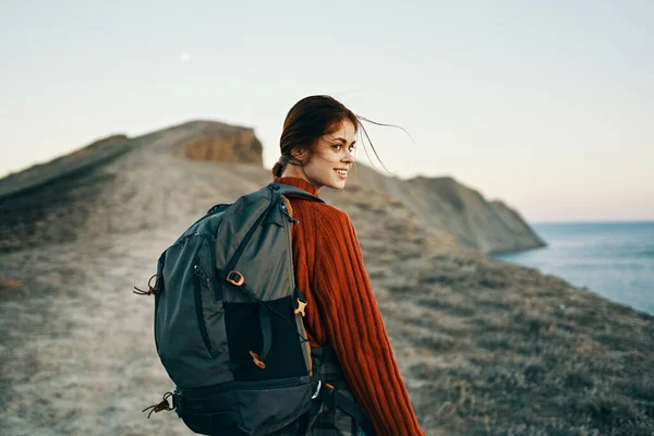 Bella donna che viaggia in montagna con uno zaino sulle spalle vicino al mare — Foto Stock