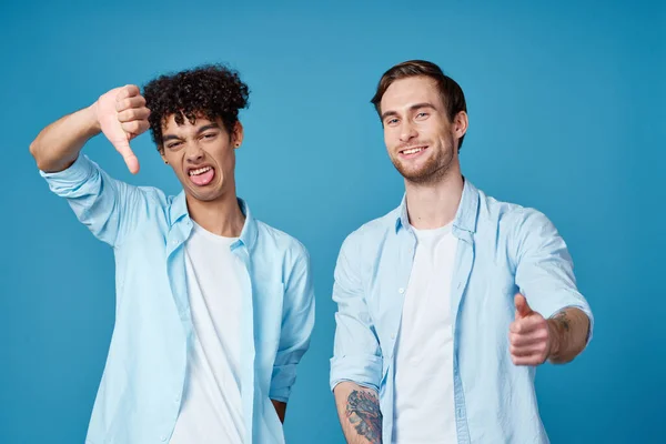 같은 셔츠를 입고 있는 두 친구와 푸른 배경에 손을 뻗고 있는 티셔츠 — 스톡 사진