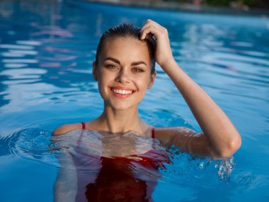 Havuzda keyifli, güzel bir kadın. Kırmızı mayo. Lüks kozmetik.
