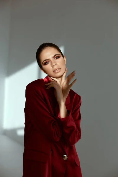 Vacker kvinna håller händer nära ansiktet charm kosmetika röd jacka — Stockfoto