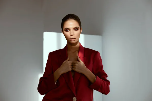 Woman in a jacket with bright makeup on her face posing in a dark room and falling light from the window — Stock Photo, Image