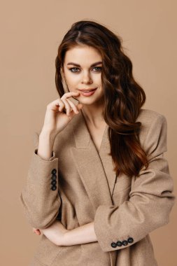 Güzel bir kadın göz kamaştırıcı bej arka planda el ele tutuşuyor.