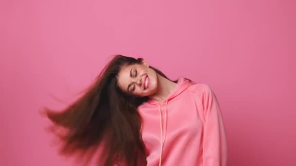 Жінка посміхається і махає волоссям, рожевий фон — стокове відео