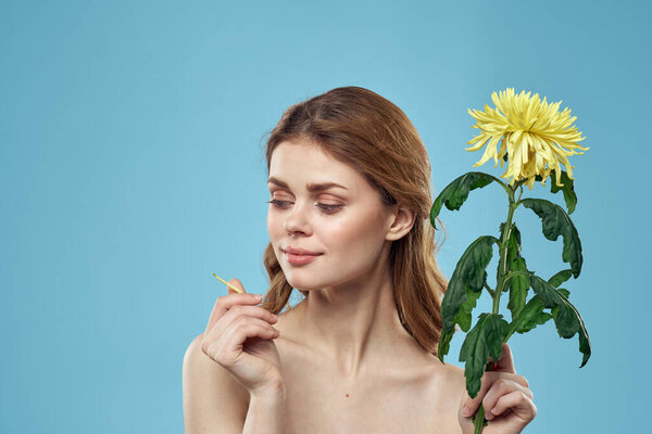 beautiful woman with yellow flower near face smiling cropped view portrait of bared shoulders