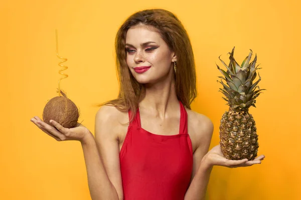 Frau mit Kokoscocktail Ananas in den Händen und kritischen Früchten Rotes T-Shirt gelber Hintergrund — Stockfoto