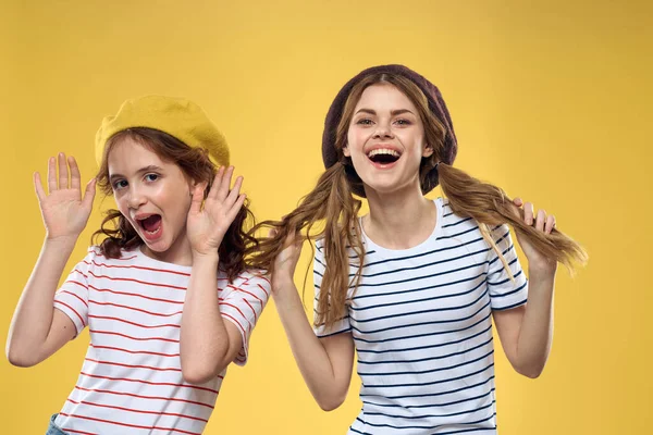 Divertido mamá e hija usando sombreros moda diversión alegría familia amarillo fondo —  Fotos de Stock