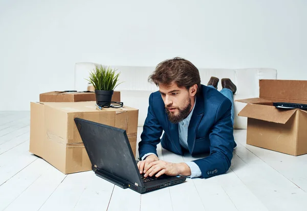 Un homme d'affaires est allongé sur le sol devant un ordinateur portable, travaille sans rien déballer — Photo