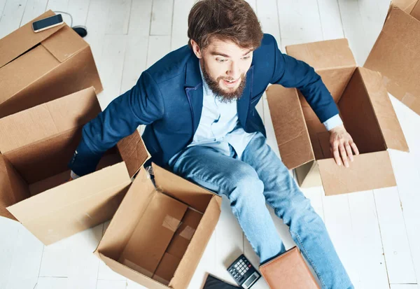 Business man with boxes sits on the office floor unpacking things