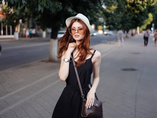 Mujer posando en la naturaleza modelo sombrero bolso vestido negro — Foto de Stock