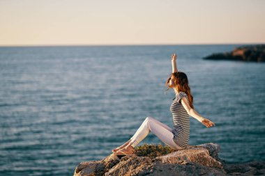Çizgili tişörtlü kadın, ellerini bezelye içinde denizin kenarına kaldırdı.