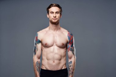 Erkek üstsüz, kaslı karın kası dövmeli, spor manzaralı.