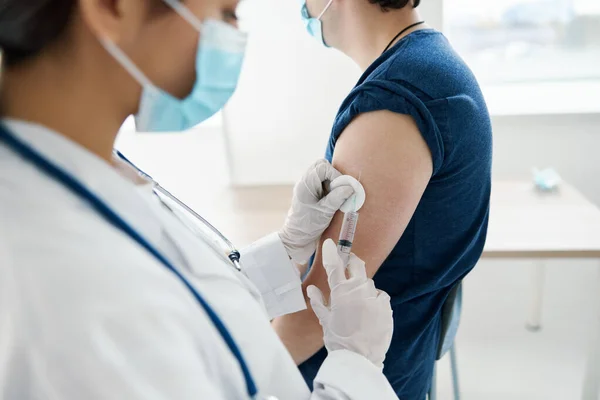 Medico tiene una siringa vicino al paziente mano e guanti protettivi covid — Foto Stock