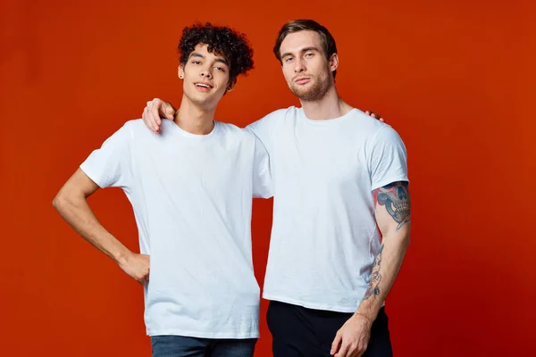 Due amici in bianco t-shirt abbracci comunicazione sfondo rosso — Foto Stock
