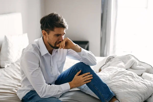 A lonely man sits on a bed In a bright room near a window top view — Stock Photo, Image