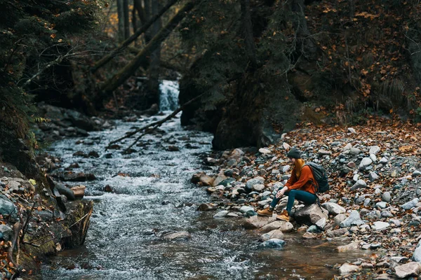 Kobieta z plecakiem i jesienią krajobraz góry las czysta woda rzeka — Zdjęcie stockowe