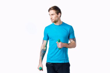 Elinde dambıl, elinde kulaklık, spor salonu olan bir adam.