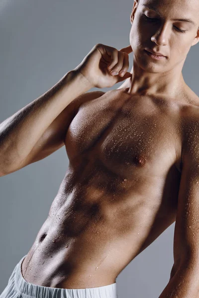 Man med en upppumpad bål på en grå bakgrund poserar biceps bodybuilder modell — Stockfoto