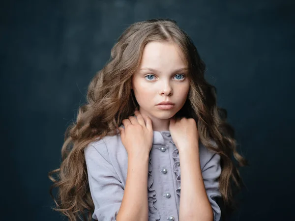 Mooi klein meisje verdrietig gezicht donker achtergrond en grijs jurk portret — Stockfoto